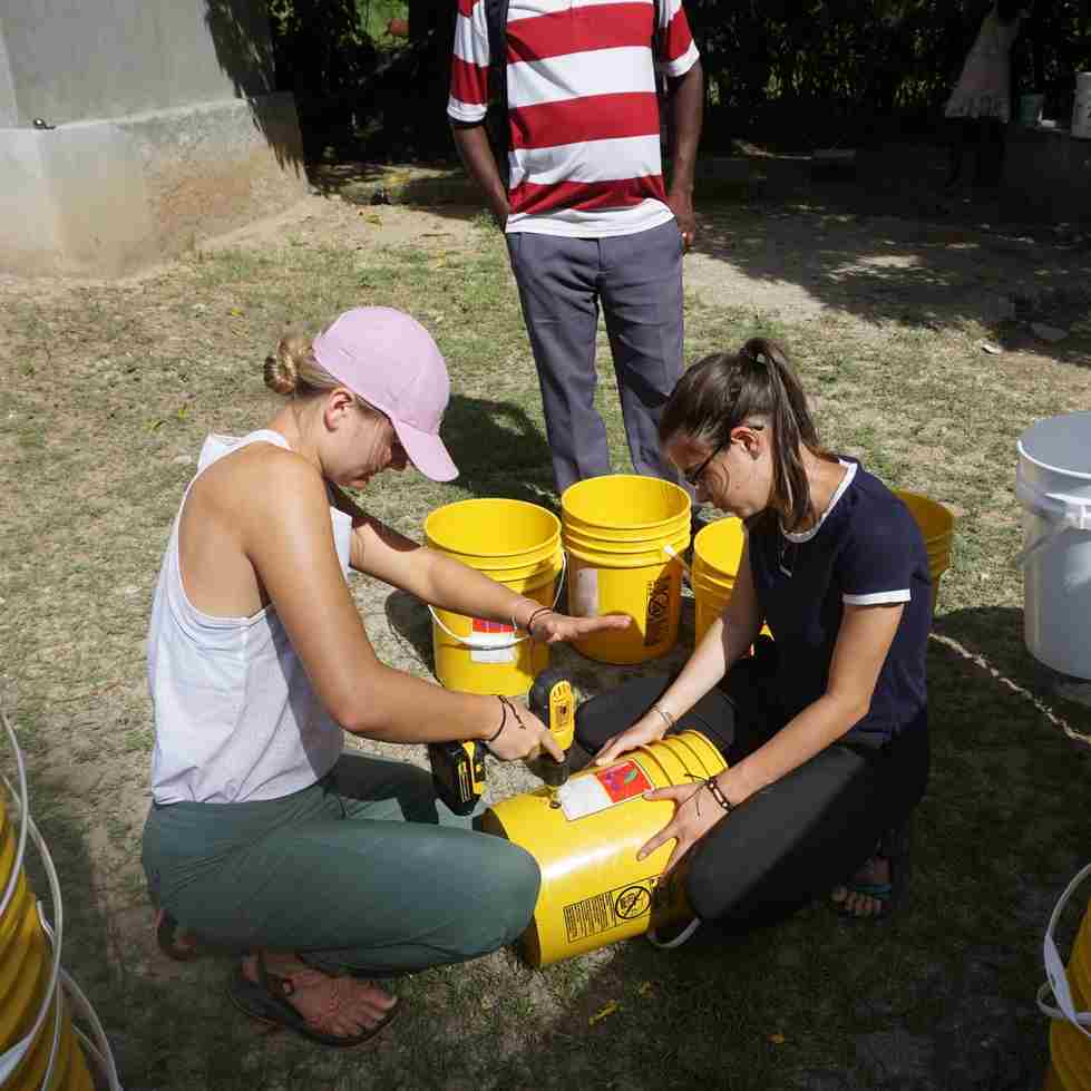 two students working on building water filters with buckets